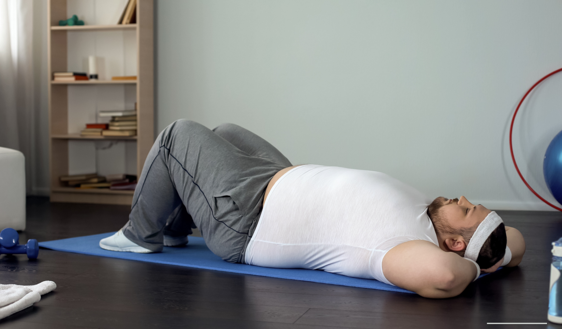A man with obesity lying on an exercise mat.