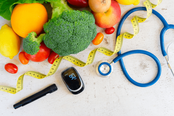 Healthy food, stethoscope, pulse ox and tape measure.
