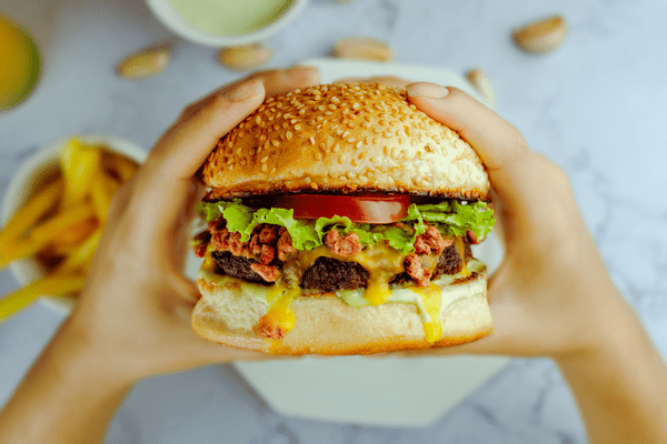 A person holding a large hamburger