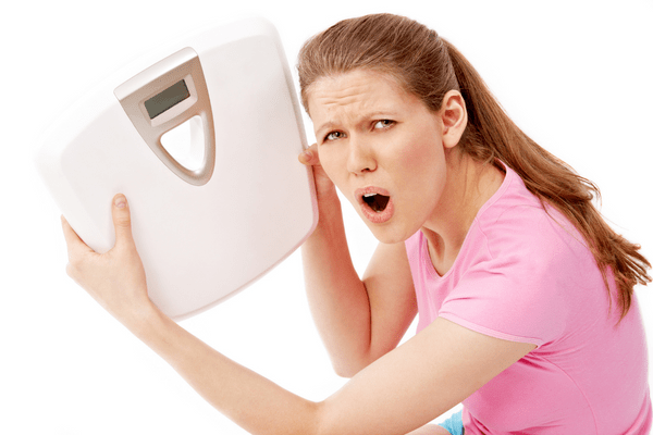 frustrated woman holding a scale after gaining weight