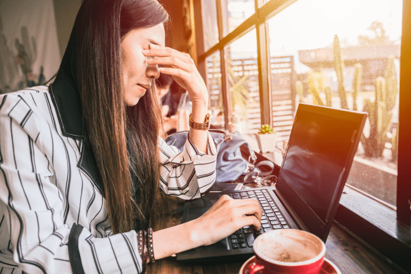 A tired women drinking coffee and using a computer