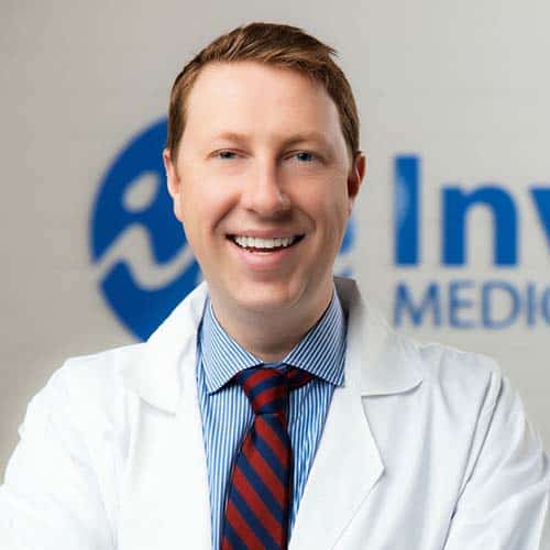 Dr Andrew Hamilton, smiling and folding arms