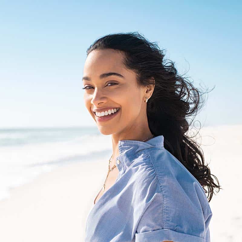 A happy woman on a beach, smiling