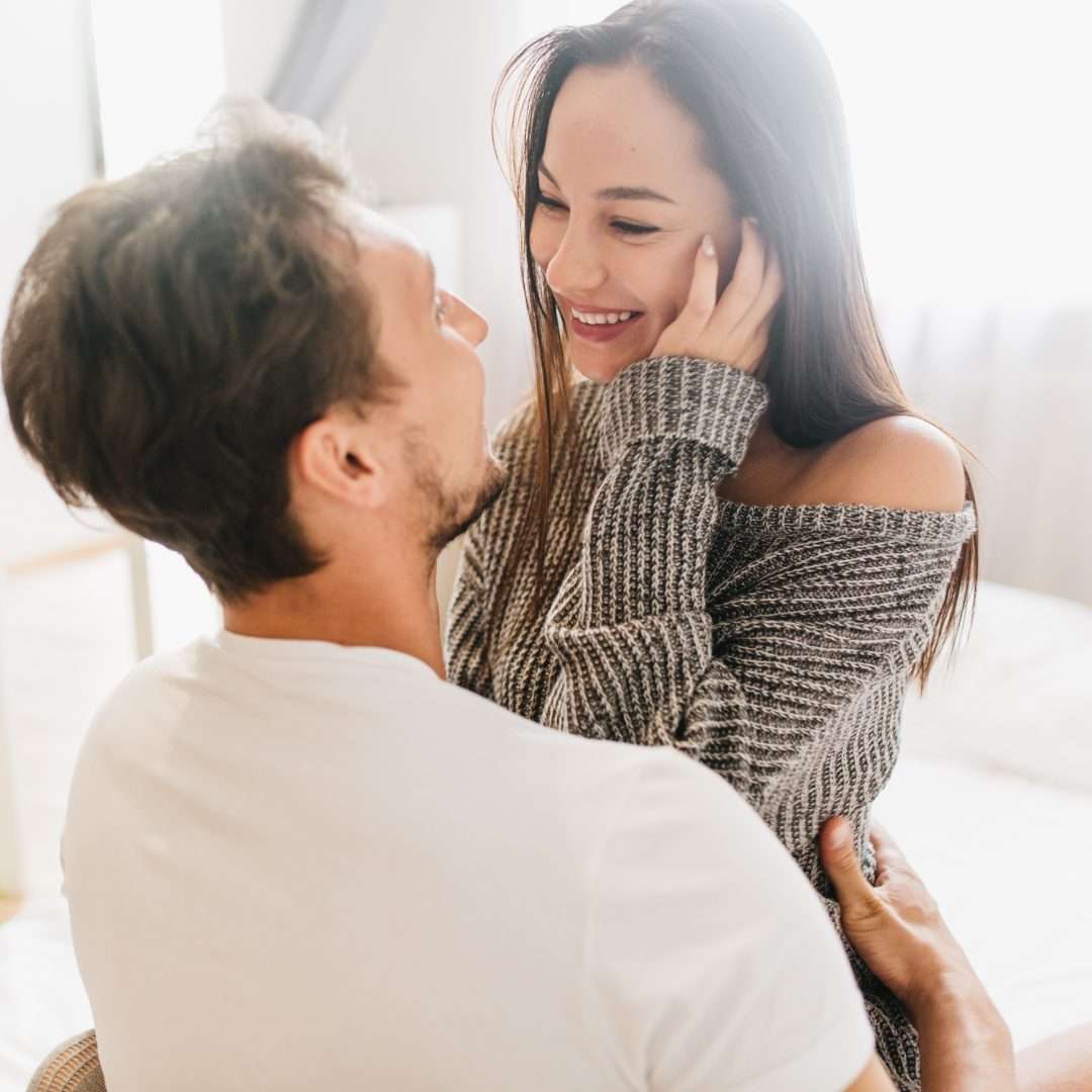 A couple embracing in a bedroom setting
