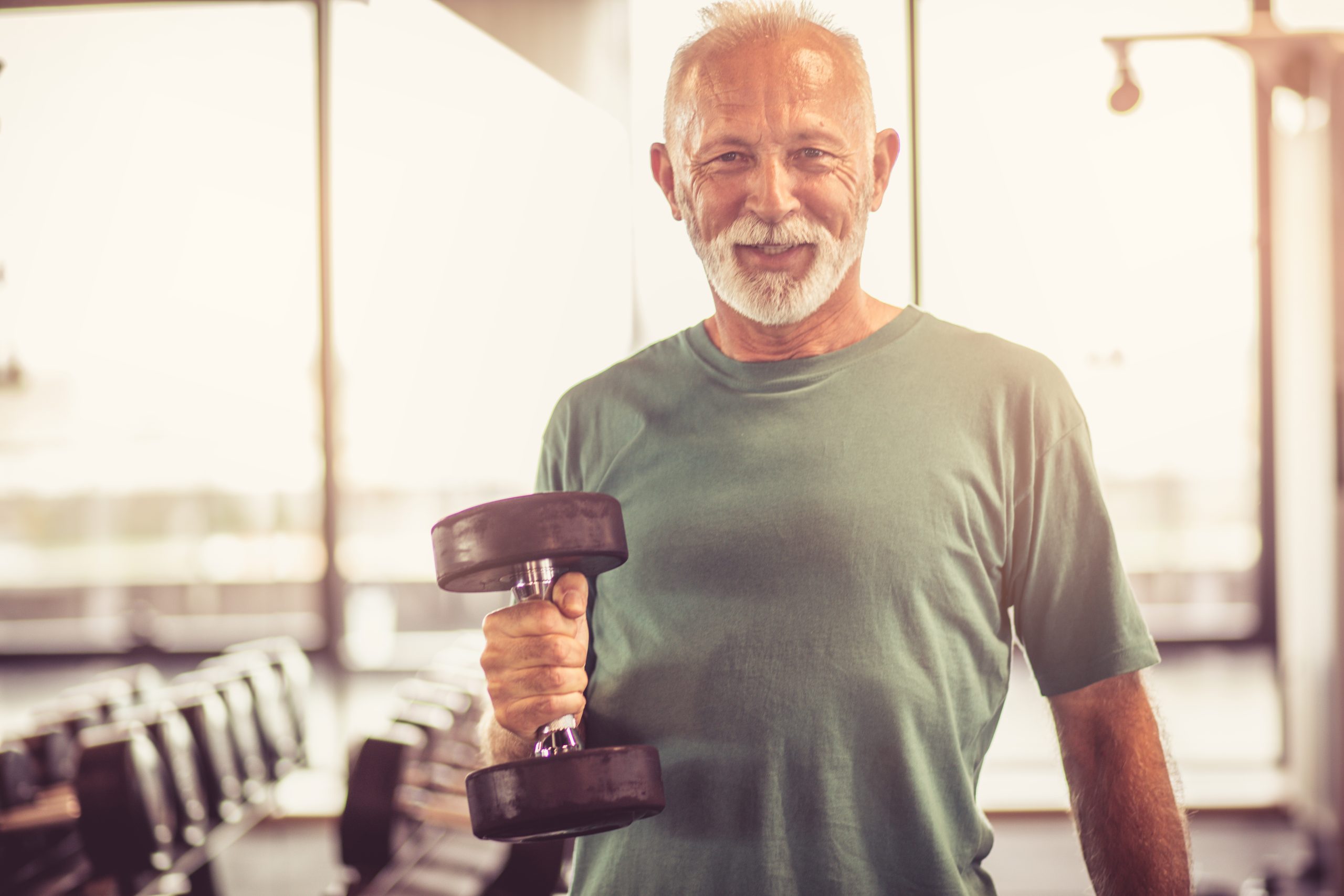 Smiling older male lifting a dumbbell