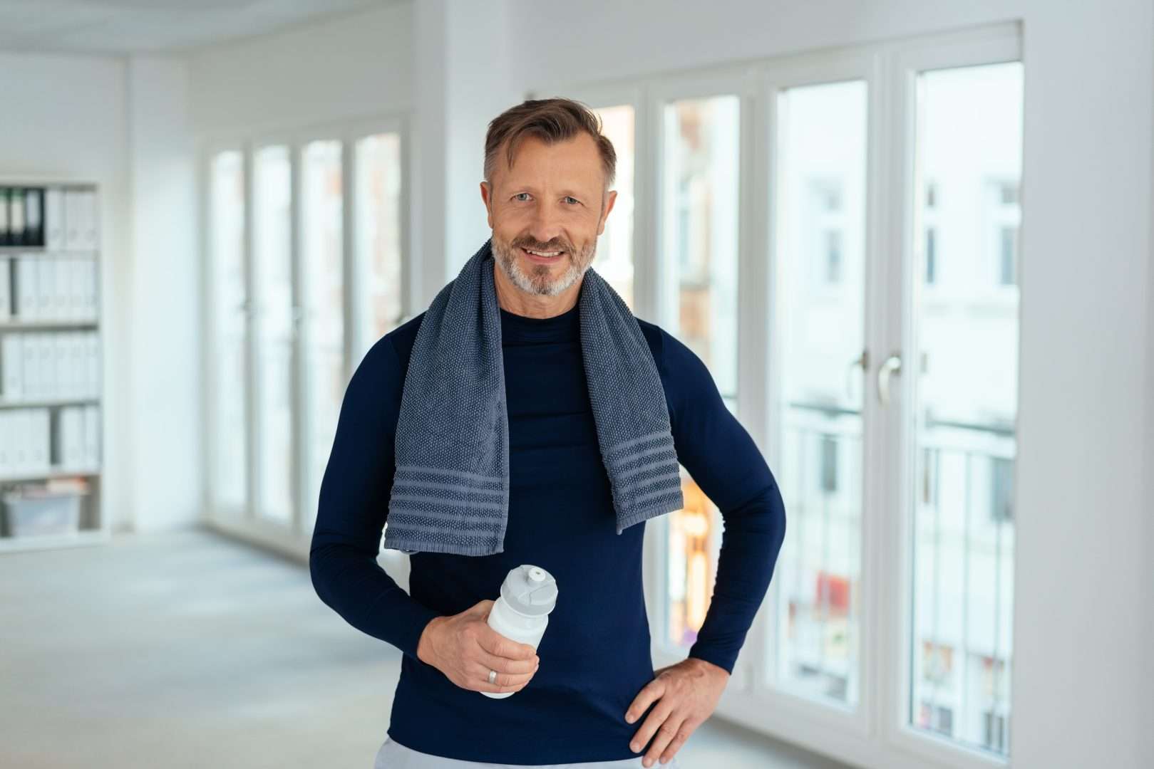 Smiling Friendly Athletic Middle-aged Man Standing Holding A Bottle
