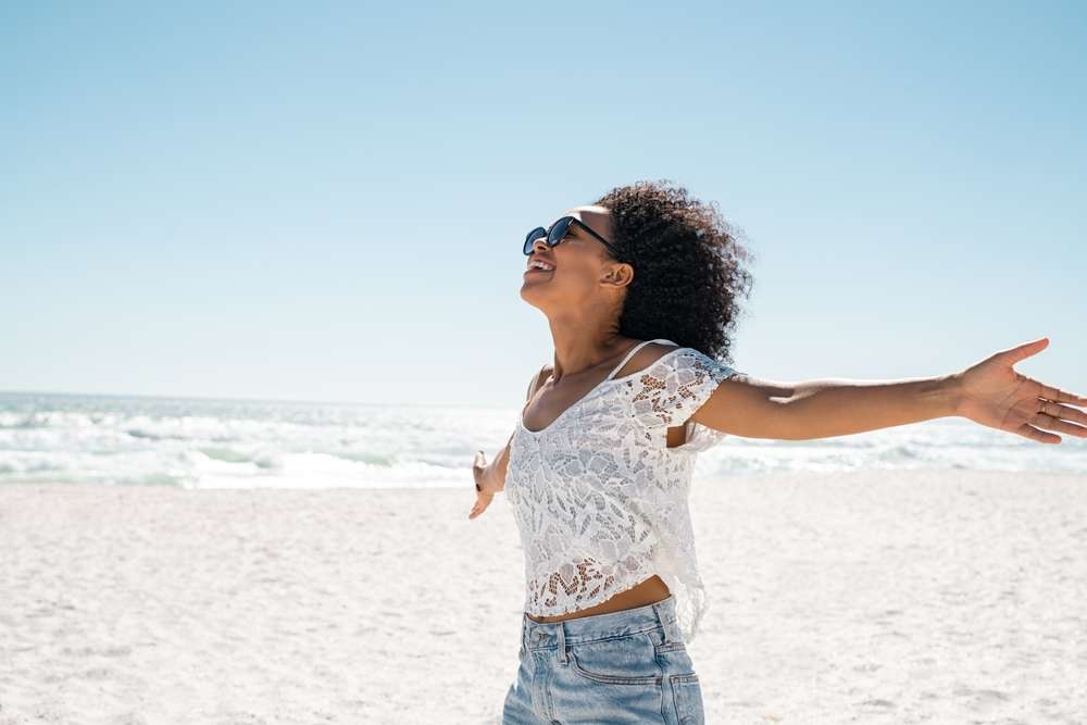 Woman with energy standing on the beach with arms wide open