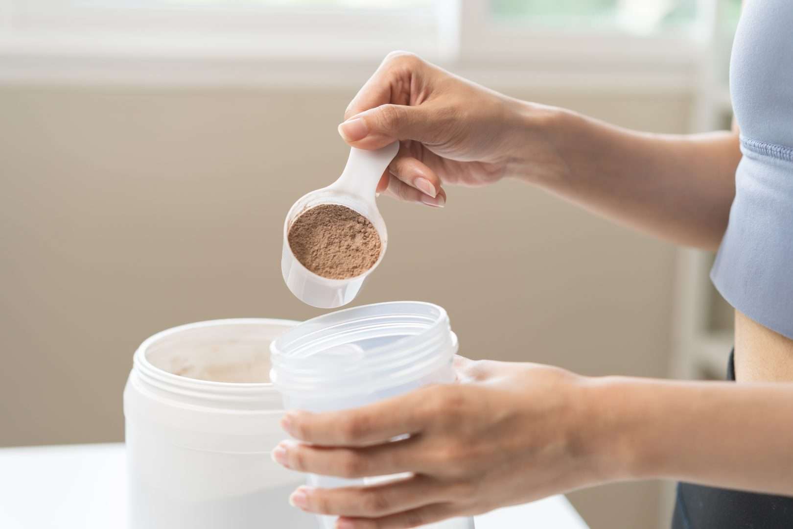 Female adding protein powder to a drink