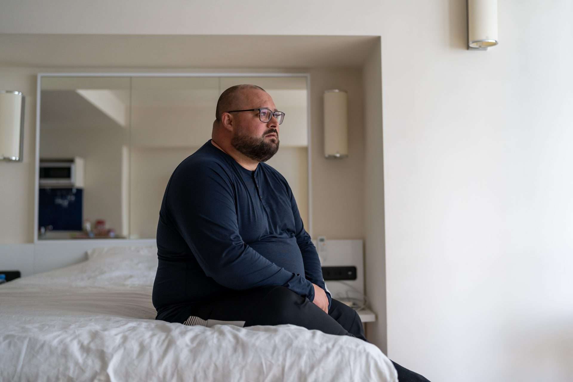 Overweight male sitting on the bed looking depressed